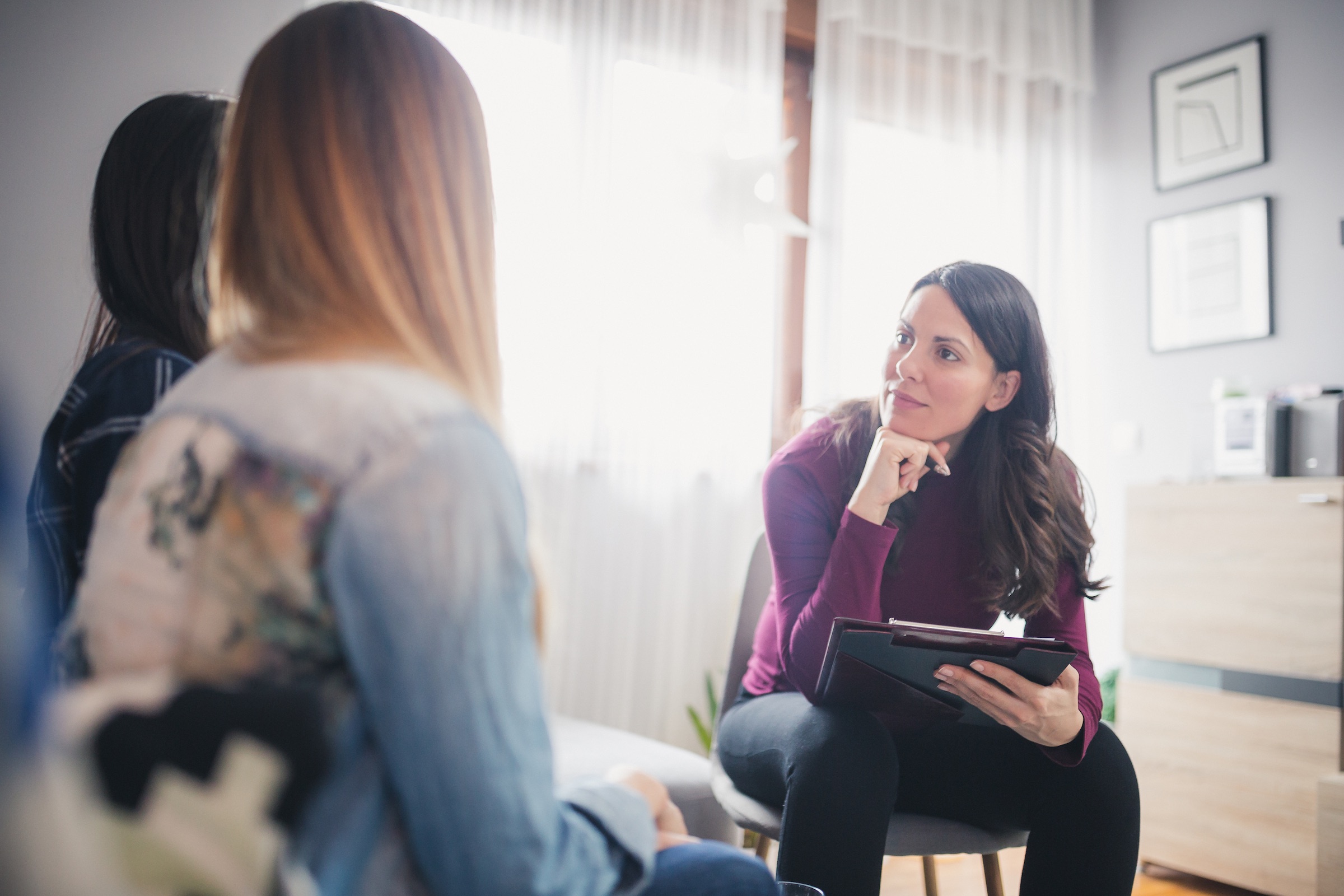 A behavioral health professional listens to a caregiver and child during a consultation.